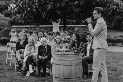 Pascal delivering a speech standing at a barrel in front of the audience.